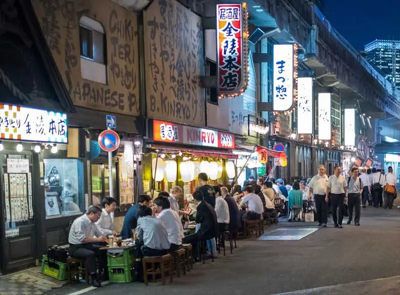 Una calle de Japón con bares y chicos sentados tomando algo